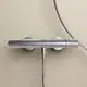 Brausethermostat von Ideal Standard in Chrom, direkt an der Wand montiert, mit Anschluss für Duschschlauch. Simple, funktionale Ausführung ohne sichtbare Regler.